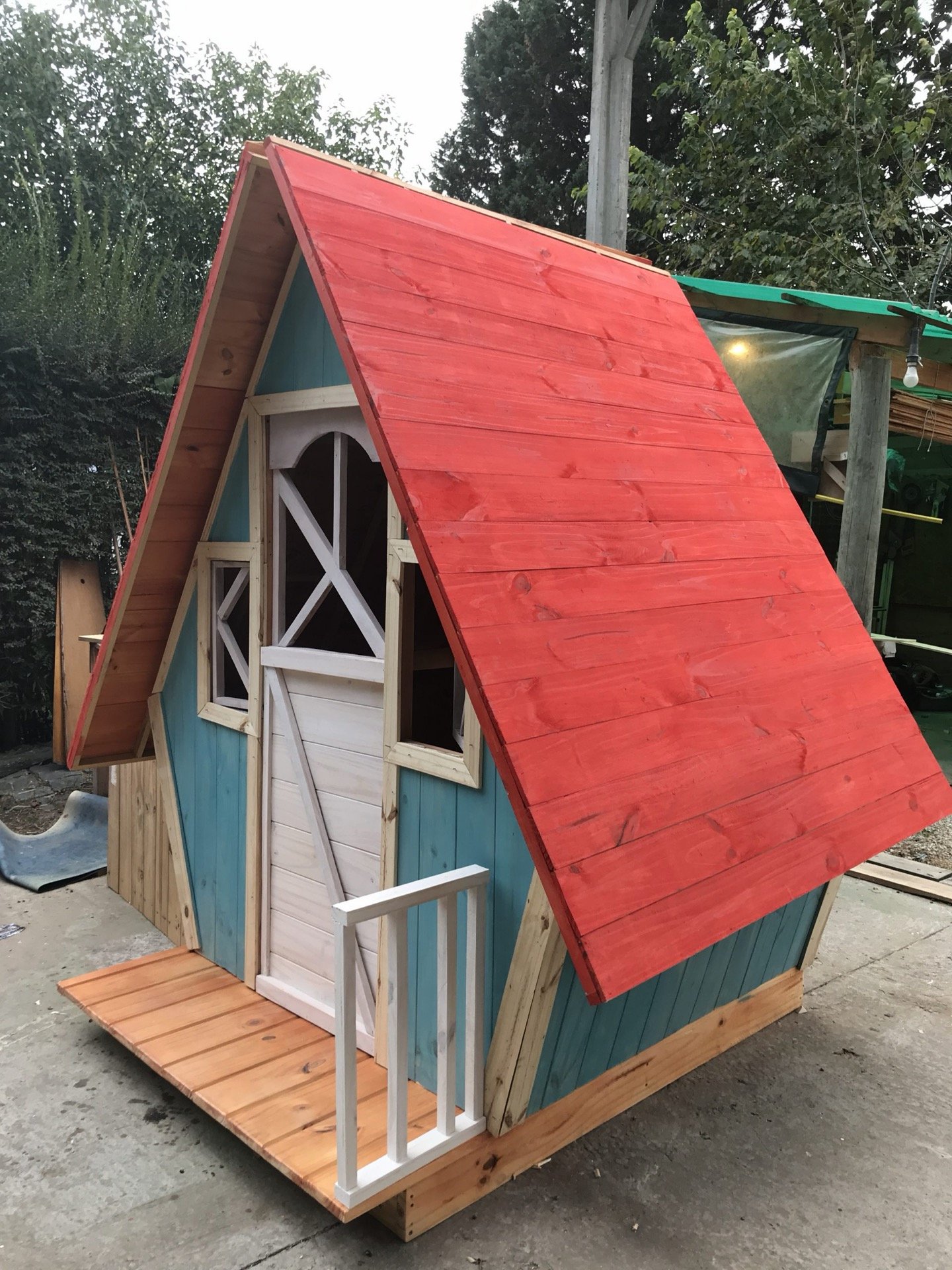 Casita en verde agua con techo rojo y deck